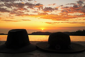 Two hats on a table with a sunset view over water. - Stunning Casa de la Roca House w/ Infinity Pool! (Ciudad Cortés)