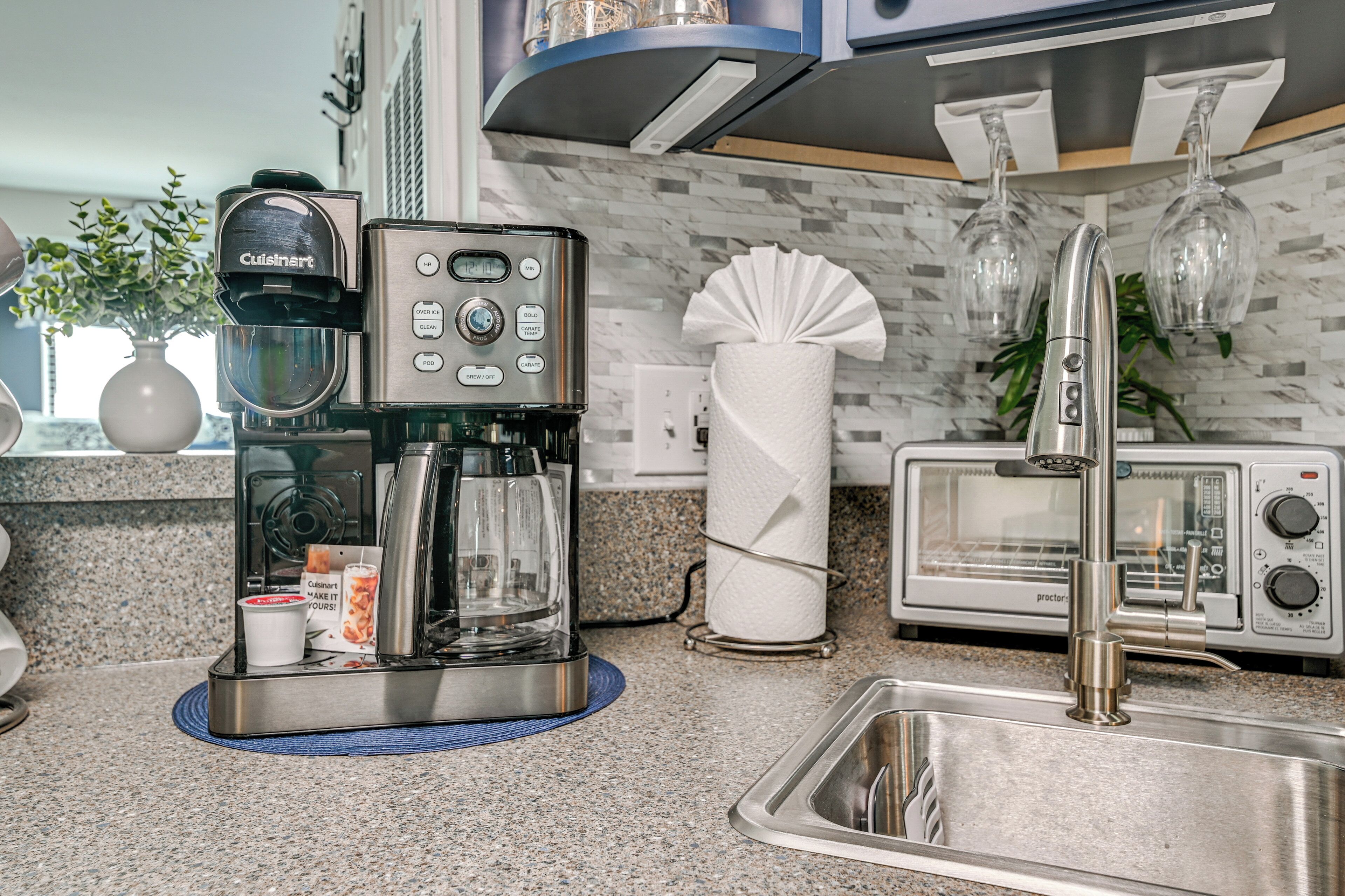 A modern kitchen with a coffee maker, toaster, and stainless steel sink.