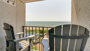 Un balcón con dos sillas Adirondack, una mesita y vista al océano.