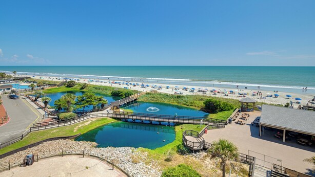 Un resort en la playa con piscina, sombrillas y un pabellón.