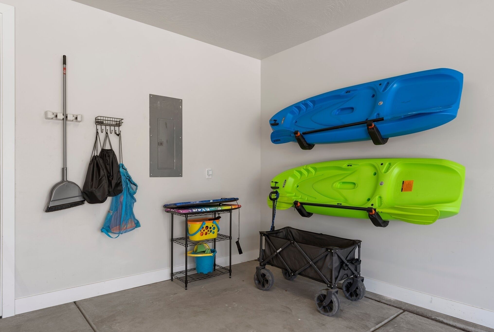A garage with two kayaks, a broom, and a stroller.