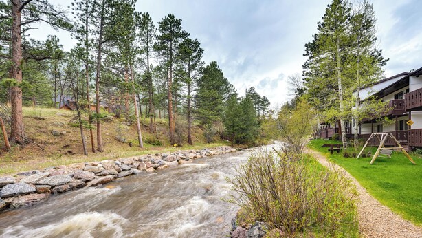 A river flowing through a forested area with a building on the right side.