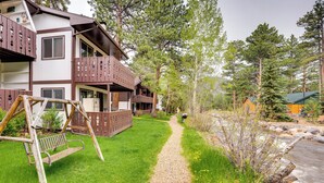 A two-story building with a gravel path leading to a wooden swing set.