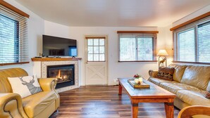 A living room with a fireplace, leather sofas, a wooden coffee table, and a television.
