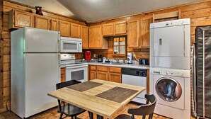Une cuisine compacte dotée de meubles en bois, d’un réfrigérateur, d’un four à micro-ondes, d’une cuisinière, d’un évier et d’un lave-linge.