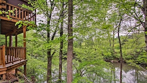 Une terrasse en bois donnant sur une zone boisée et surplombant un plan d’eau paisible.
