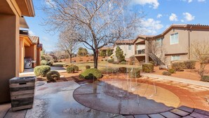 A residential area with a patio, a tree, and a building with a tiled roof. - Splash Pad Place #29 3 Bedroom Home (Ivins)