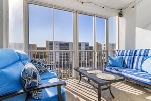 En balkon med to blå sofaer, et lille bord og udsigt til bygninger gennem store vinduer.