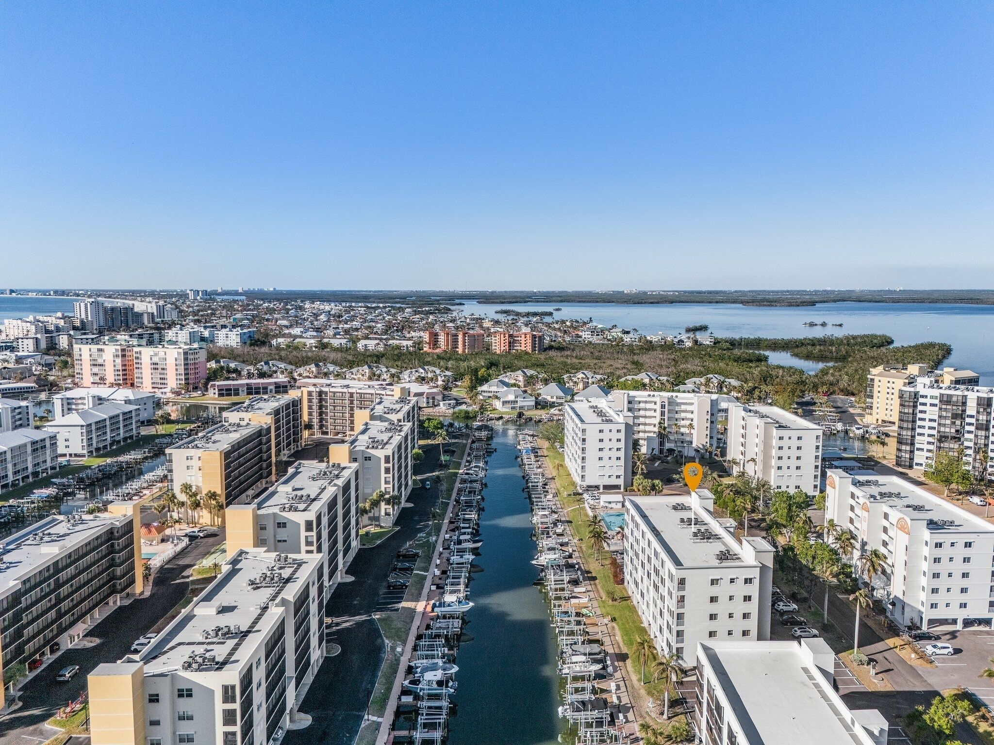 A marina with boats docked, surrounded by modern buildings and a clear view of the water.