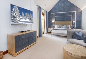 A modern bedroom with a large bed, a sofa, a wooden dresser, and a painting of a snowy landscape. - Ritz Carlton Vail #402 4 Bedroom Condo (Vail)