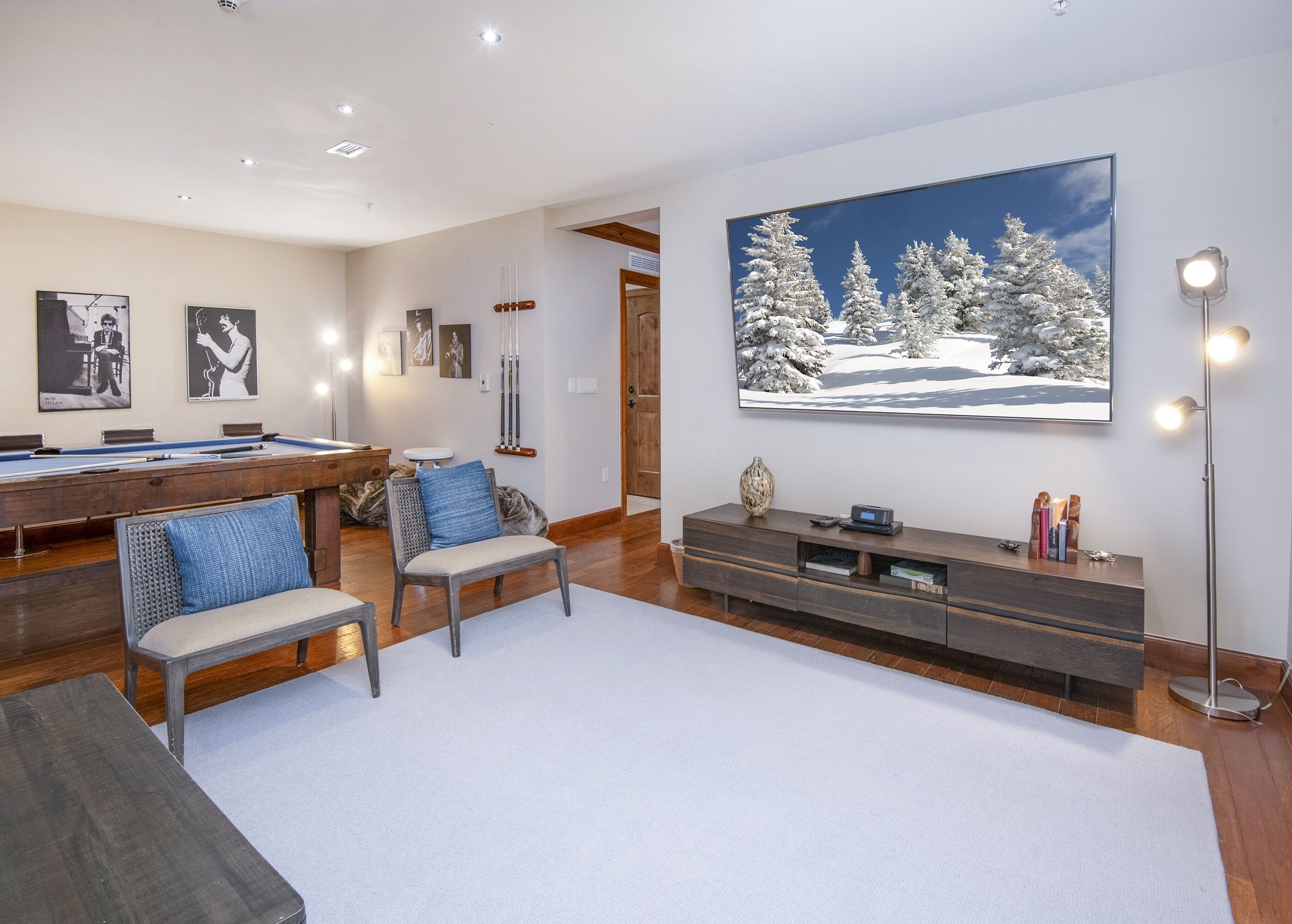 A spacious living room with a pool table, comfortable seating, a large TV, and a modern entertainment unit.