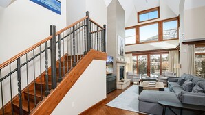 A spacious living area with a wooden staircase, a gray sectional sofa, and a fireplace. - Ritz Carlton Vail #402 4 Bedroom Condo (Vail)