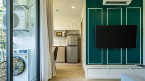 Una cucina moderna con forno a microonde integrato, frigorifero e televisione a schermo piatto montata a parete.