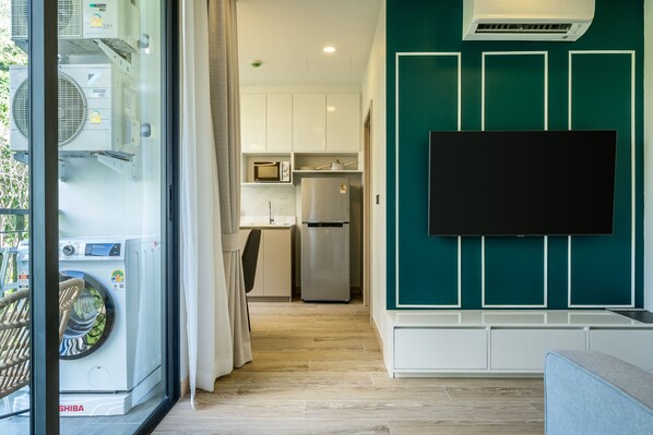 Una cocina moderna con microondas integrado, refrigerador y televisor de pantalla plana montado en la pared.