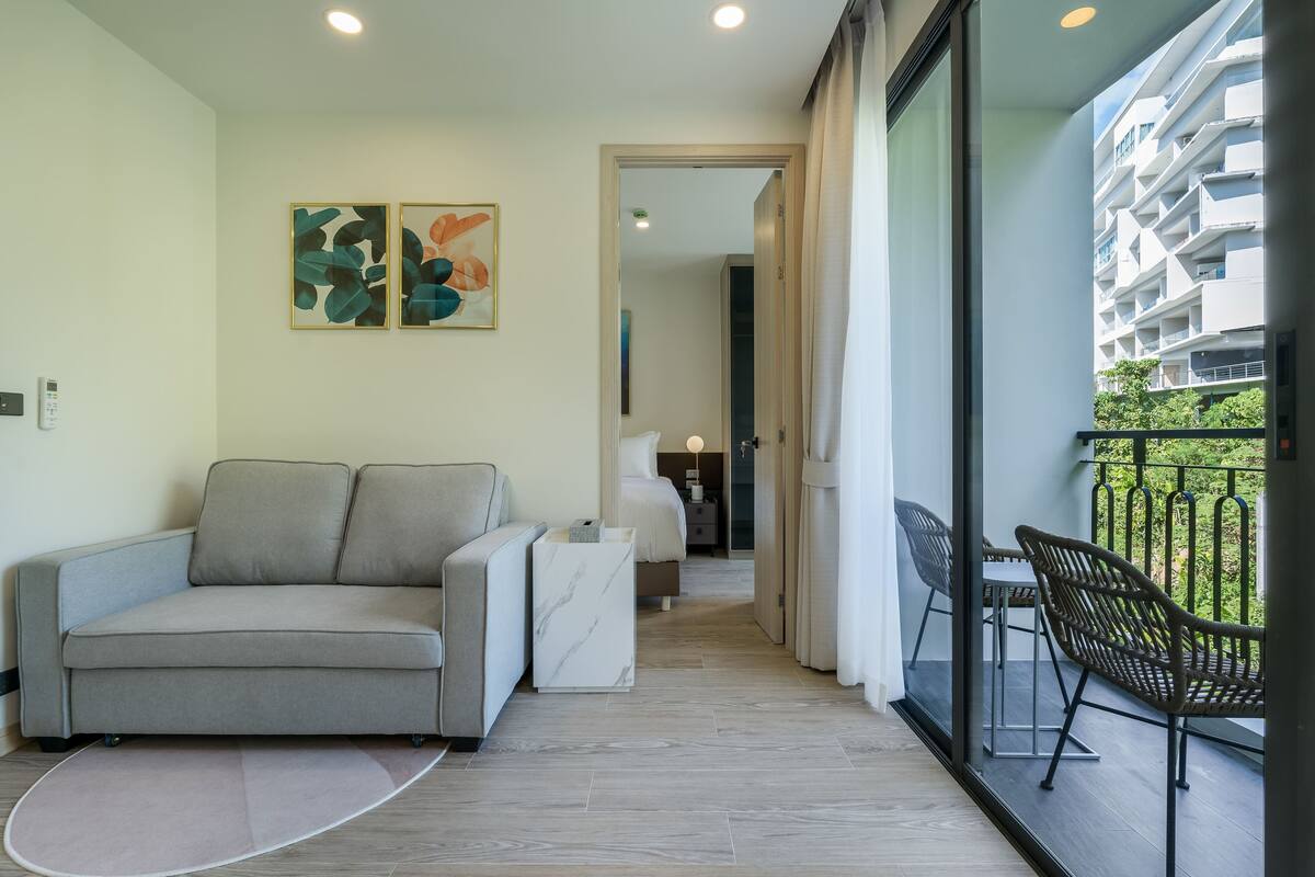 Una sala de estar moderna con un sofá, una mesita y un balcón con sillas.