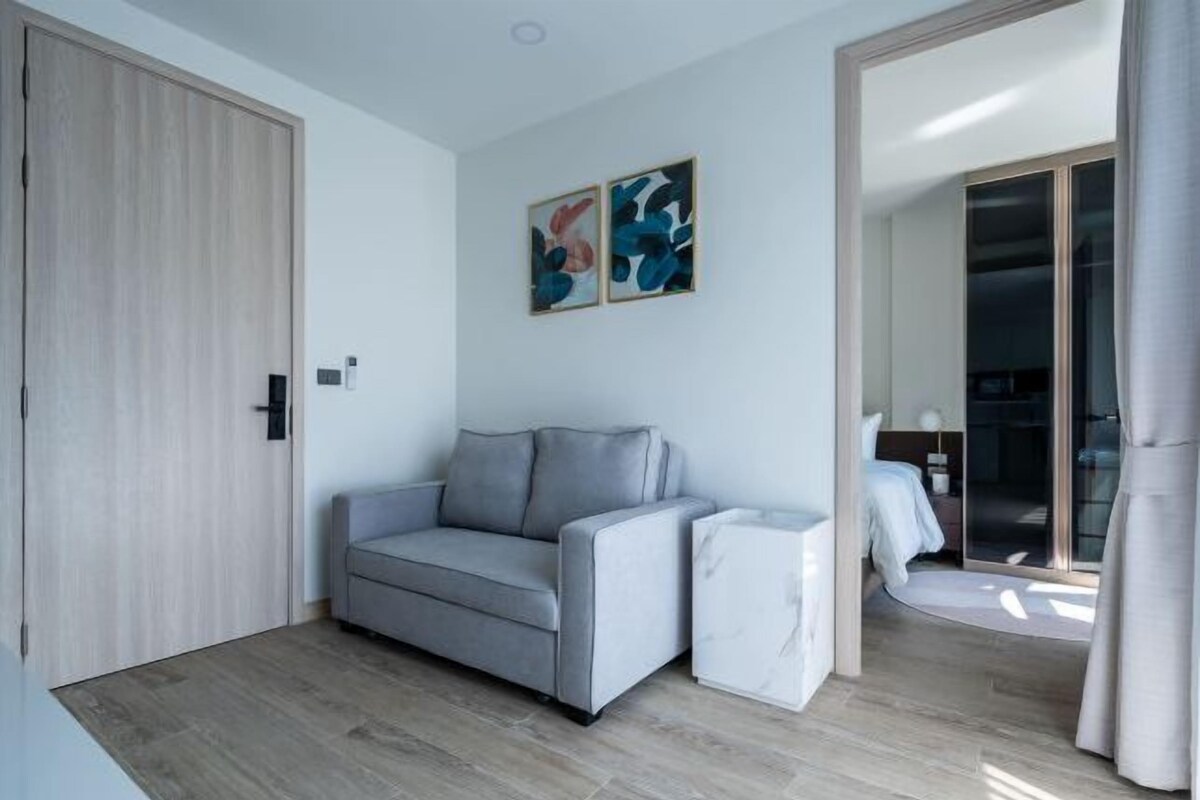 A modern living room with a grey sofa, a small white side table, and abstract art on the wall.