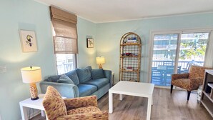 Una sala de estar con sofá, sillón, mesa de centro y una mesita auxiliar con lámpara.