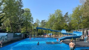 A swimming pool with a water slide and a lifeguard tower. - Forest view holiday house with private jacuzzi (Hoenderloo)