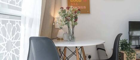 Ein moderner Essbereich mit einem runden Tisch, zwei schwarzen Stühlen und einer Blumenvase.