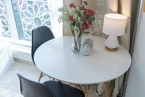 Sit comfortably at the round table with two chairs, surrounded by a beautiful floral arrangement and a stylish lamp.