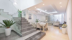 A modern interior with a staircase, dining area, and seating. - StayShort - Nice Villa in Gardenia, Jebel Ali for Family of 5! (Jebel Ali)