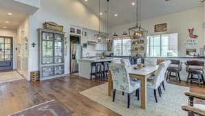 A spacious kitchen with a central island, white cabinetry, and a dining area with a wooden table and patterned chairs. - LBJ Waterfront Escape | Private Dock & sleeps 16! (Kingsland)