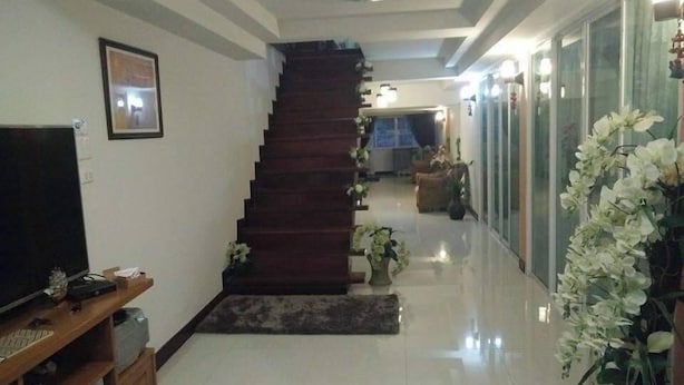 A staircase leading to a second floor, a television on the left, and a hallway with a glass door on the right. - Napakarn (Mae Chan)