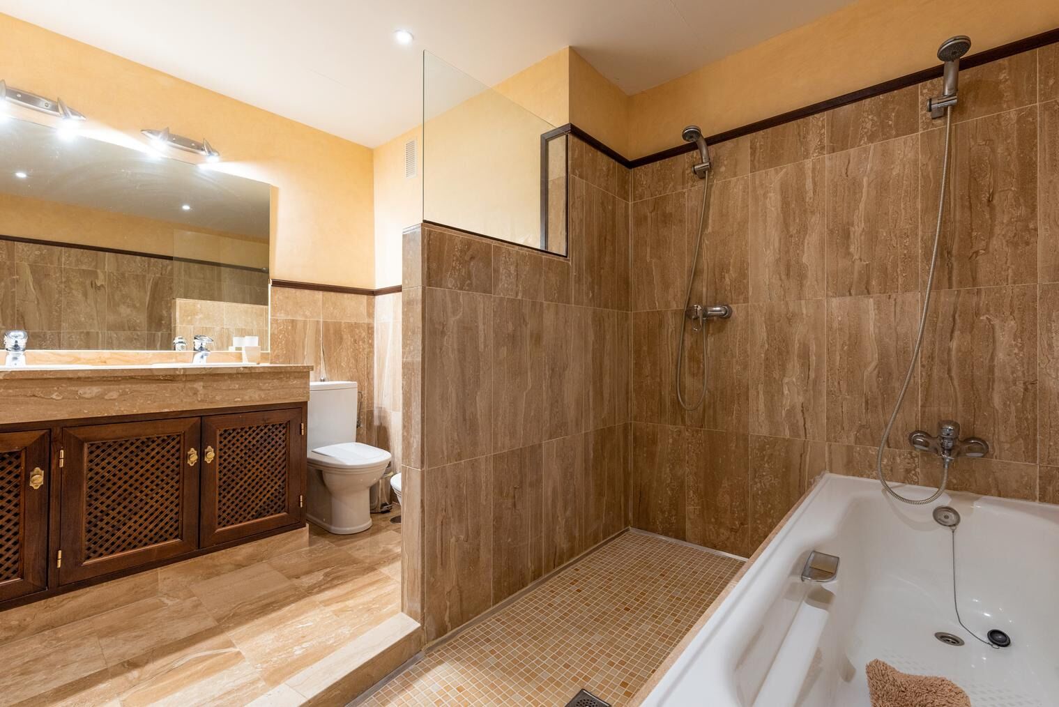 Et moderne badeværelse med bruseniche, badekar og toilet.