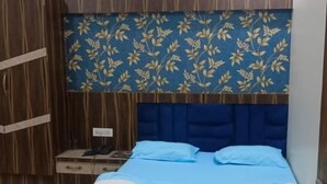 A bedroom with a bed, wooden wardrobe, and a nightstand. - Hotel SR Siddhivinayak  (Mathura)