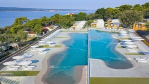 Ett semesterhotell med en stor pool, solstolar och utsikt över havet.