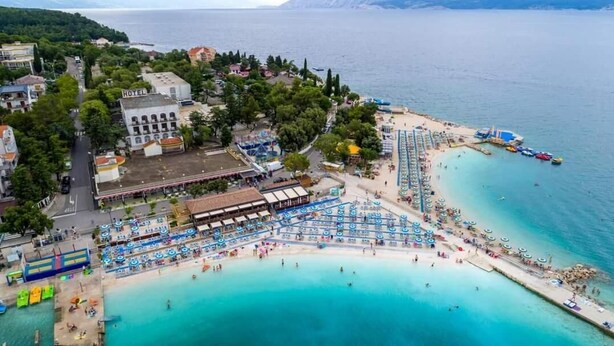 Ett flygbildsbild av ett hotell vid kusten med flera badområden, en strand och en brygga.