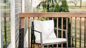 A wooden deck with a white cushioned chair. - Sunset Serenity Suite (Myerstown)