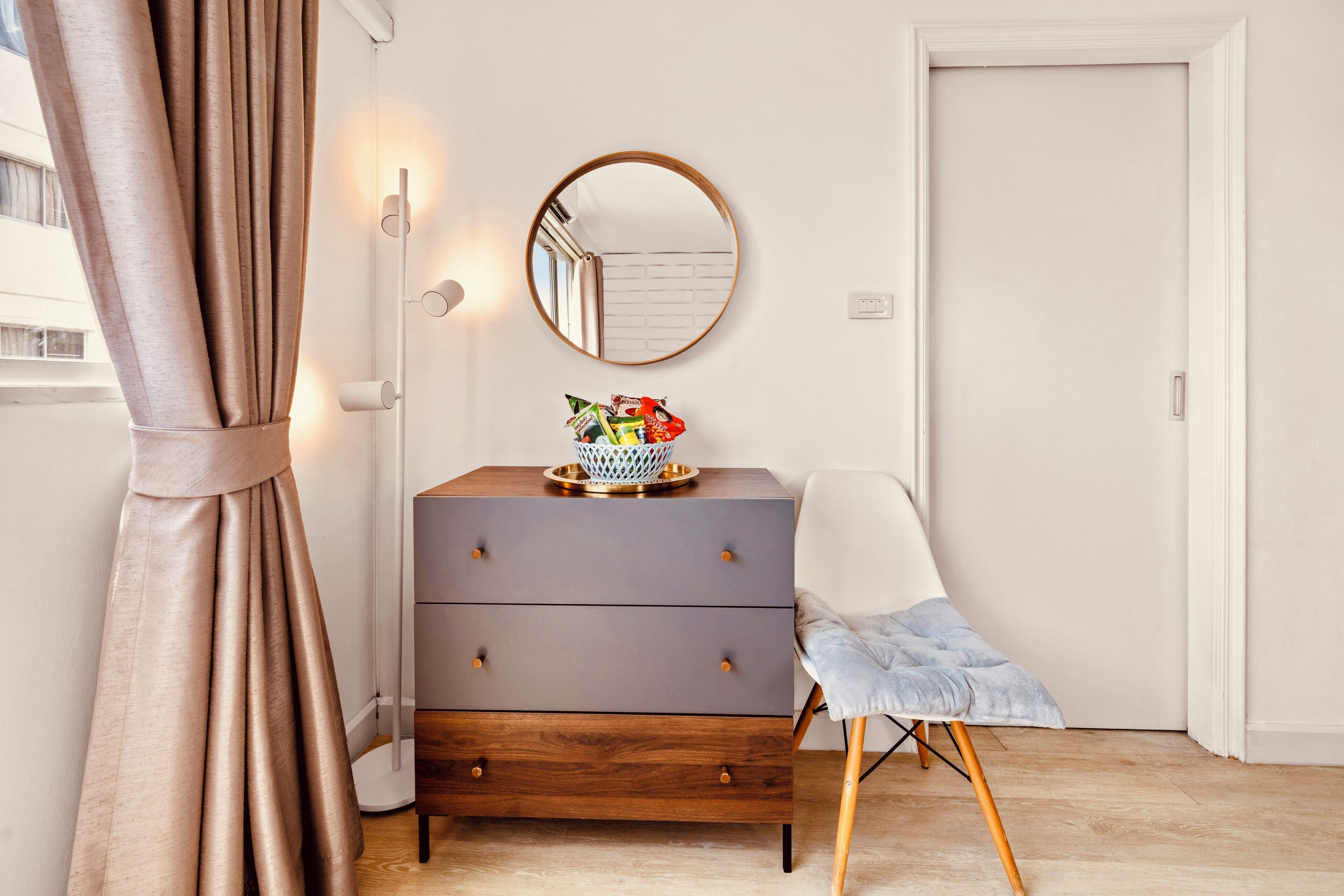 Une pièce comprenant une commode en bois, une chaise, un miroir et une porte.