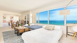 A modern bedroom with a large bed, a desk, and a view of the ocean.