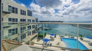 A modern hotel with a rooftop pool, glass railings, and a view of the marina. - Beach Vibes Ocean View Condo (Oranjestad)