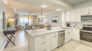 Una cocina moderna con armarios blancos, una isla grande y vistas al océano.