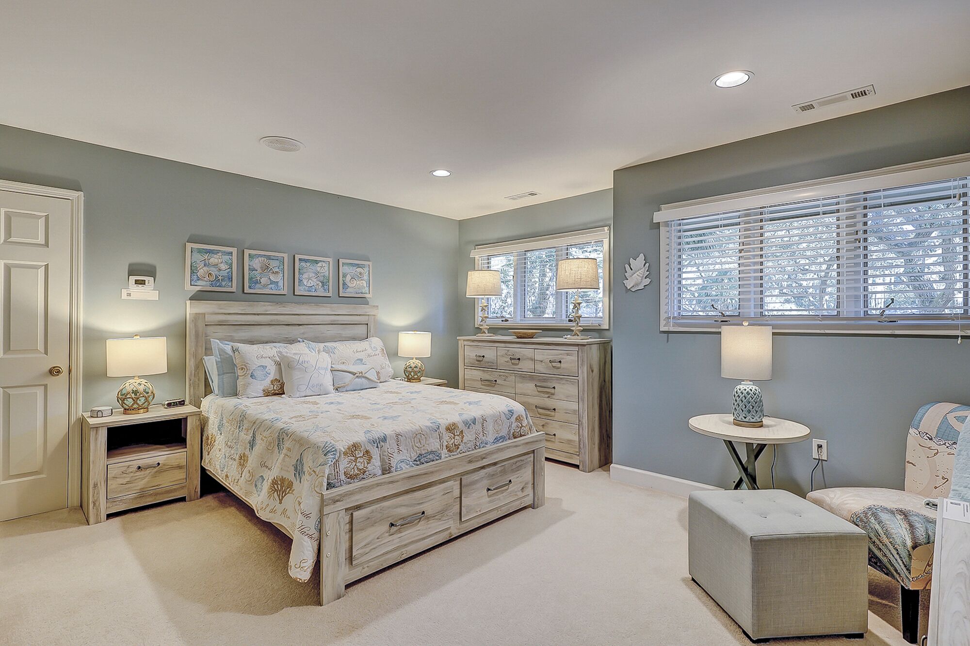 A bedroom with a bed, two nightstands, a dresser, a round table, and a bench.