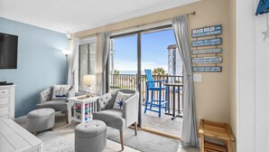 A modern living room with a balcony, a TV, and a sign with beach rules. - A208 at The Myrtle Beach Resort (Myrtle Beach)
