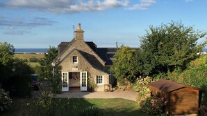 A stone house with a gabled roof, a wooden shed, and a well-maintained garden. - Charming cottage, sea and garden, close to the D-Day landing beaches, sleeps 6 (Quinéville)