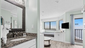 Et moderne badeværelse med bordplade i granit, et stort spejl og en vaskemøbel.