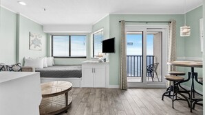 Et moderne værelse med seng, skrivebord, rundt bord og balkon med udsigt.