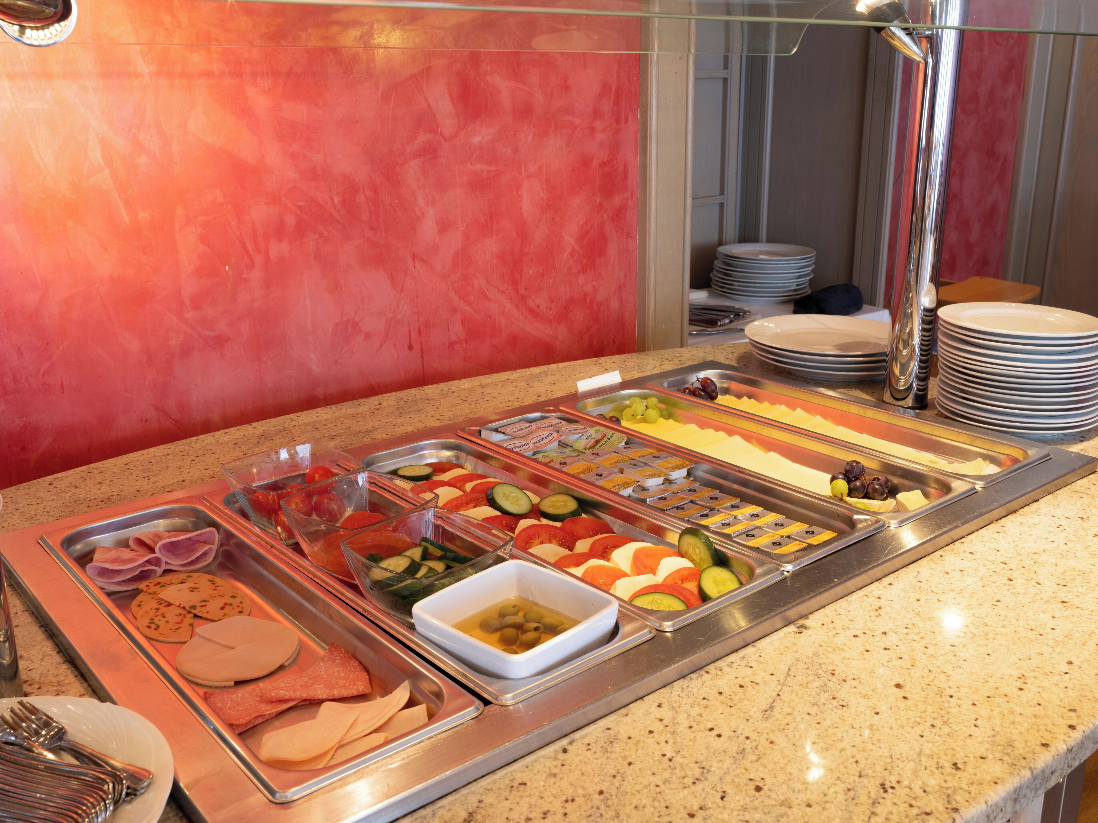 A buffet with various food options including meats, cheeses, fruits, and vegetables.
