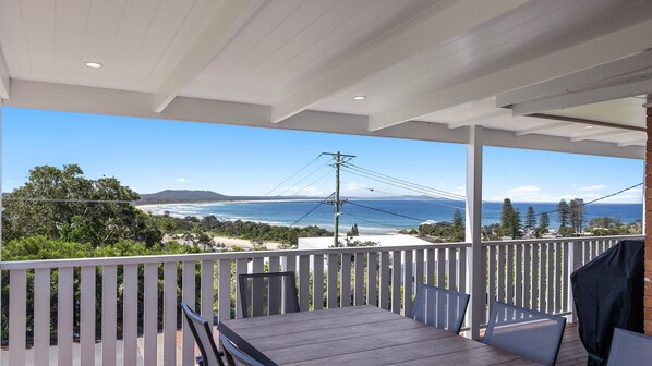 A covered outdoor area with a view of the ocean and beach.