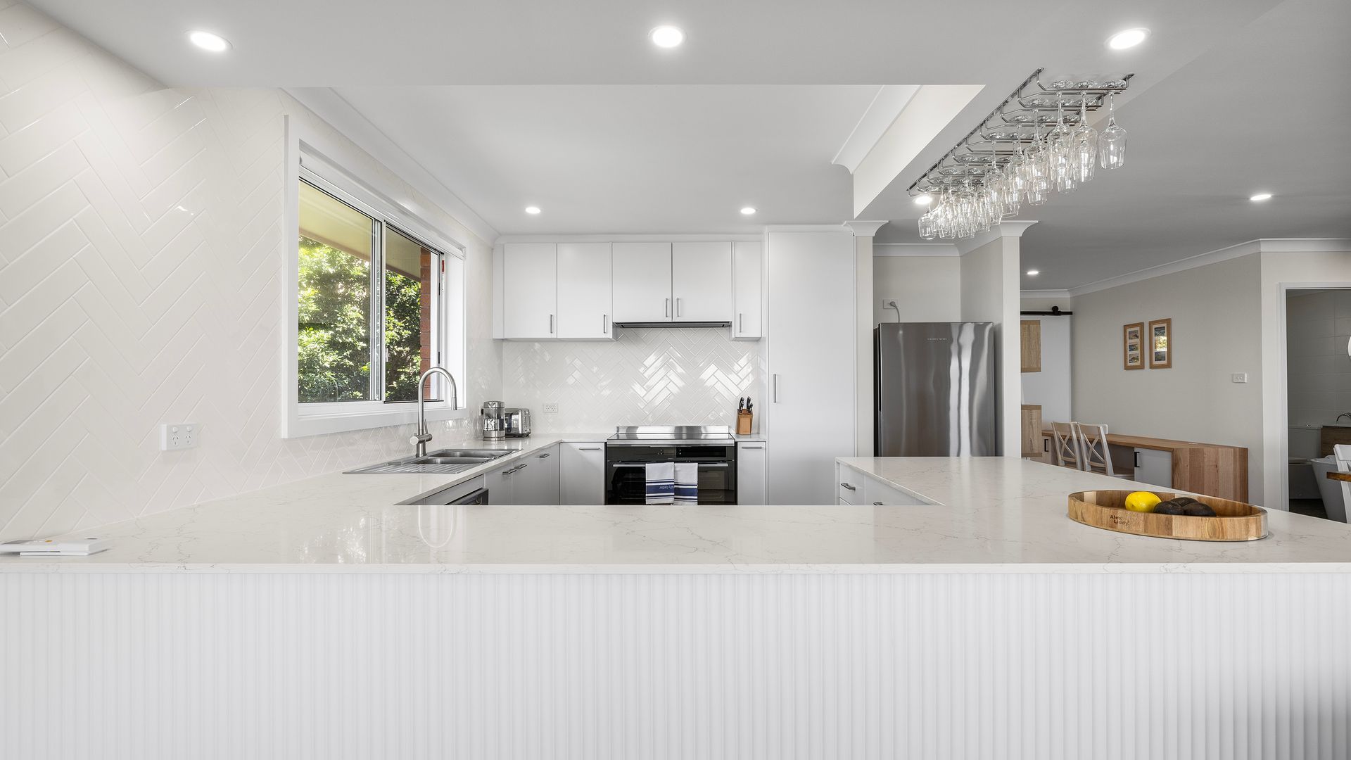 A modern kitchen with white cabinetry, a central island, and a built-in oven.