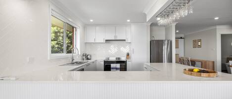 A modern kitchen with white cabinetry, a central island, and a built-in oven.