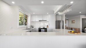 A modern kitchen with white cabinetry, a central island, and a built-in oven.