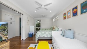 Une chambre à coucher avec un lit, un ventilateur de plafond, une fenêtre et un téléviseur.