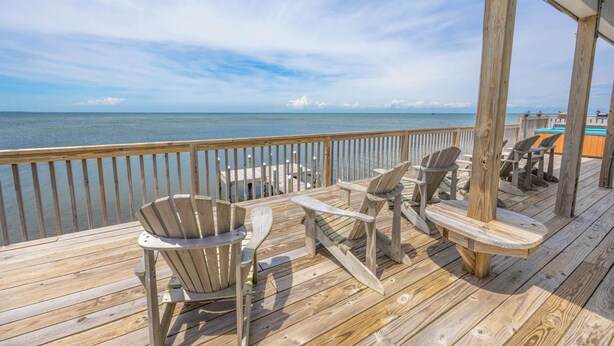 A wooden deck with Adirondack chairs overlooking a body of water. - Soundfront Home in Frisco with Hot Tub, Private Dock and Windsurfing Access (Frisco)