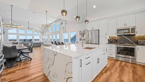 A modern kitchen with white cabinetry, a marble island, and stainless steel appliances. - Premier Soundfront w/ Pool, Hot Tub, Elevator, EV Charger, Theater & Game Rooms (Avon)