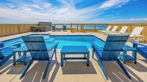 A rooftop pool area with blue lounge chairs and a view of the ocean. - Premier Soundfront w/ Pool, Hot Tub, Elevator, EV Charger, Theater & Game Rooms (Avon)